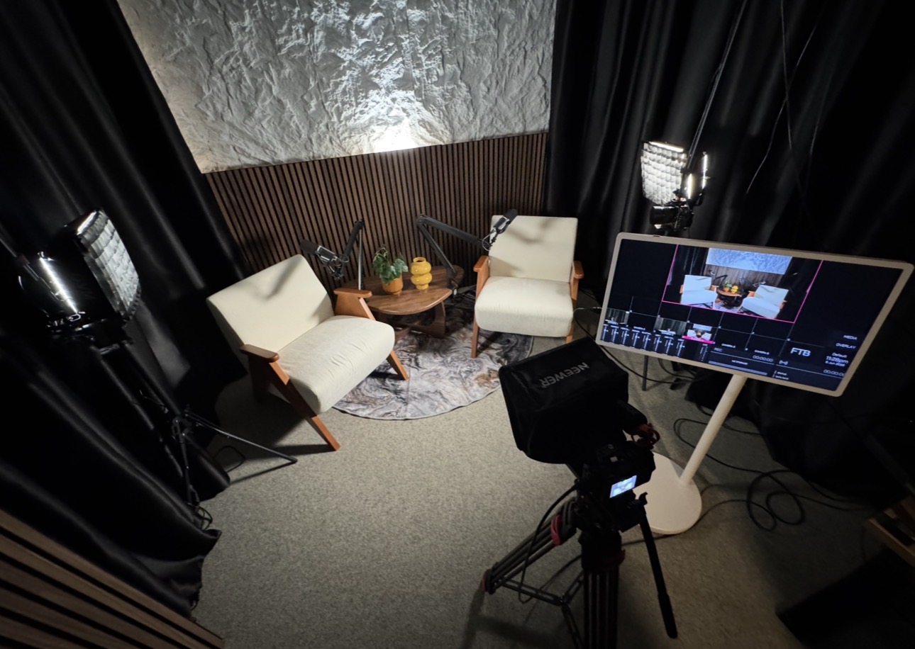 Podcast and interview recording area with two chairs, broadcast mics, and the live-switch monitor